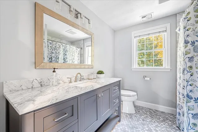 a bathroom with a granite countertop sink a toilet and a mirror