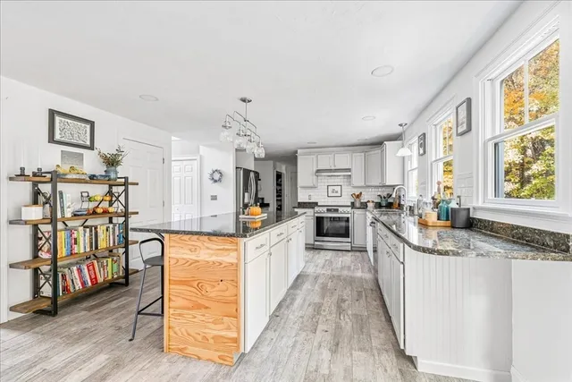 a large kitchen with stainless steel appliances granite countertop a lot of counter space and wooden floors