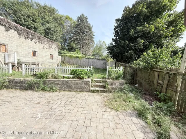 a view of a yard with plants and a bench