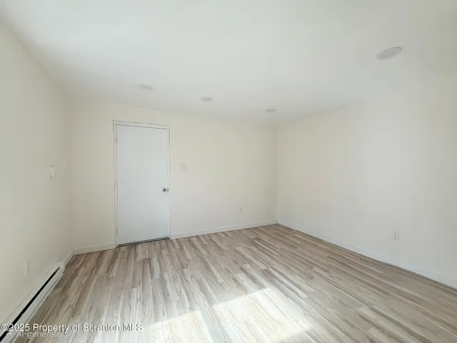 a view of a room that has wooden floor and white walls