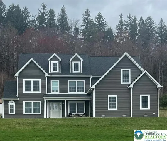 a view of a brick house next to a yard with big trees