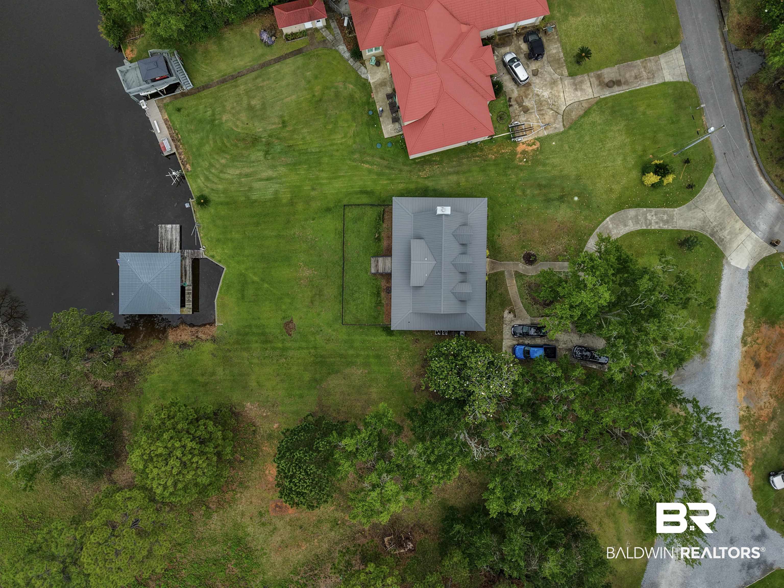 12171 Marguerite Drive Coden, AL 36523 - Photo 38 of 44 Waterfront property featuring a private boat house with a covered slip, a boat lift, and an expansive lawn
