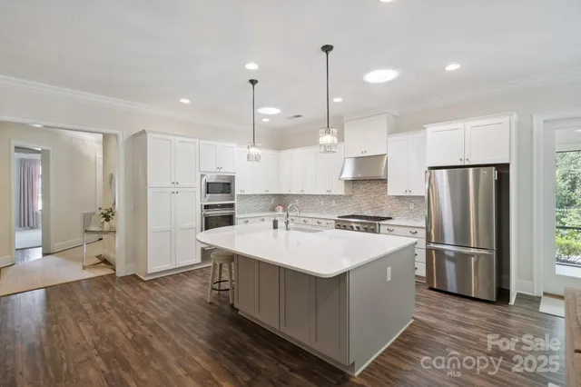 a large kitchen with stainless steel appliances a refrigerator and a stove top oven