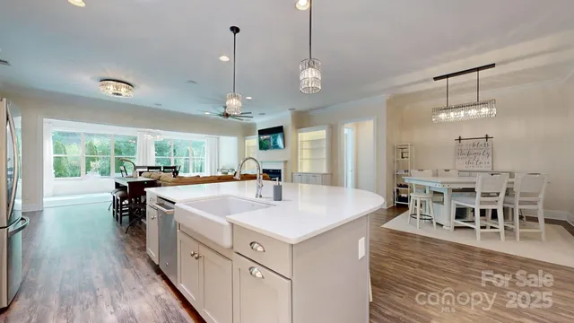 a large kitchen with kitchen island a island a sink a counter space wooden floor and stainless steel appliances