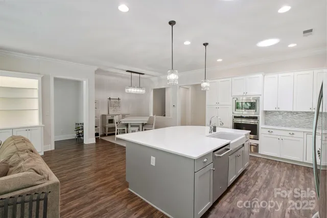 a large kitchen with kitchen island a stove a sink a center island and wooden floor