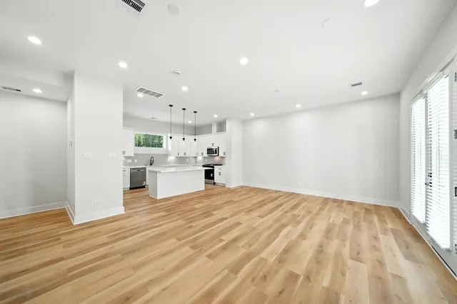 a view of a kitchen with kitchen island a sink wooden floor and view living room