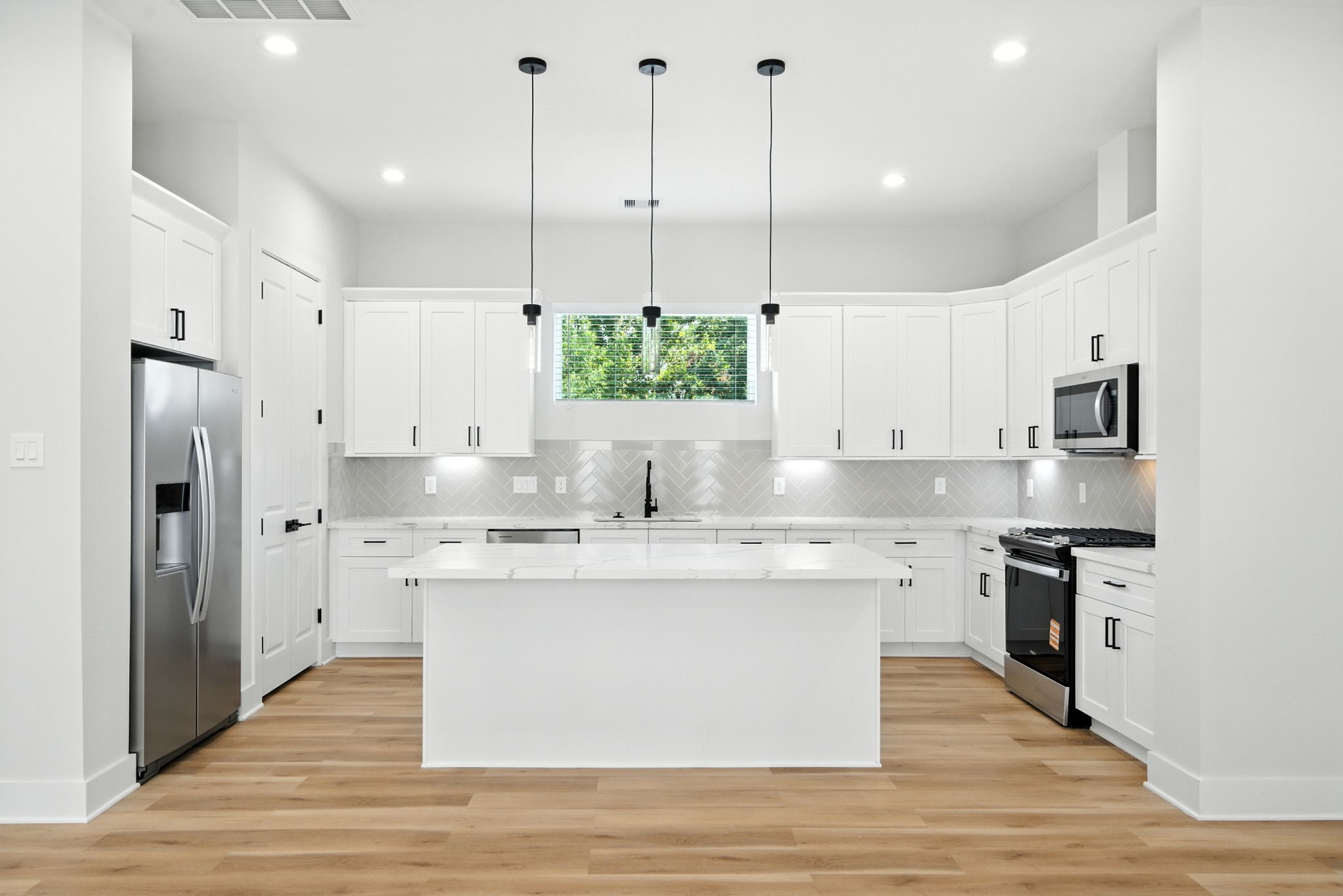 2304 Hoskins Drive, Unit D Houston, TX 77080 - Photo 13 of 41 a large kitchen with stainless steel appliances kitchen island white cabinets and wooden floors