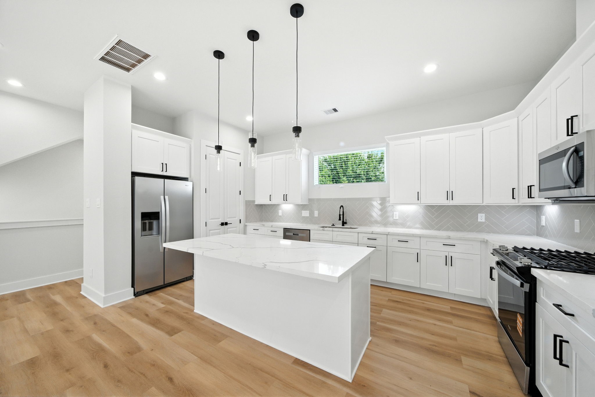 2304 Hoskins Drive, Unit D Houston, TX 77080 - Photo 17 of 41 a large kitchen with stainless steel appliances kitchen island granite countertop a sink a stove a refrigerator and island with wooden floor