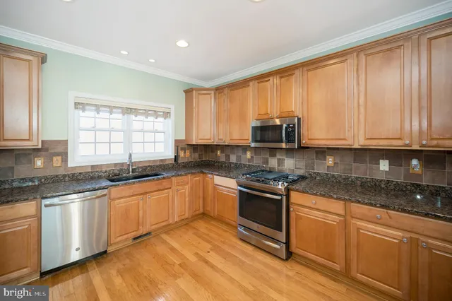 a kitchen with stainless steel appliances granite countertop a refrigerator a sink a stove and oven