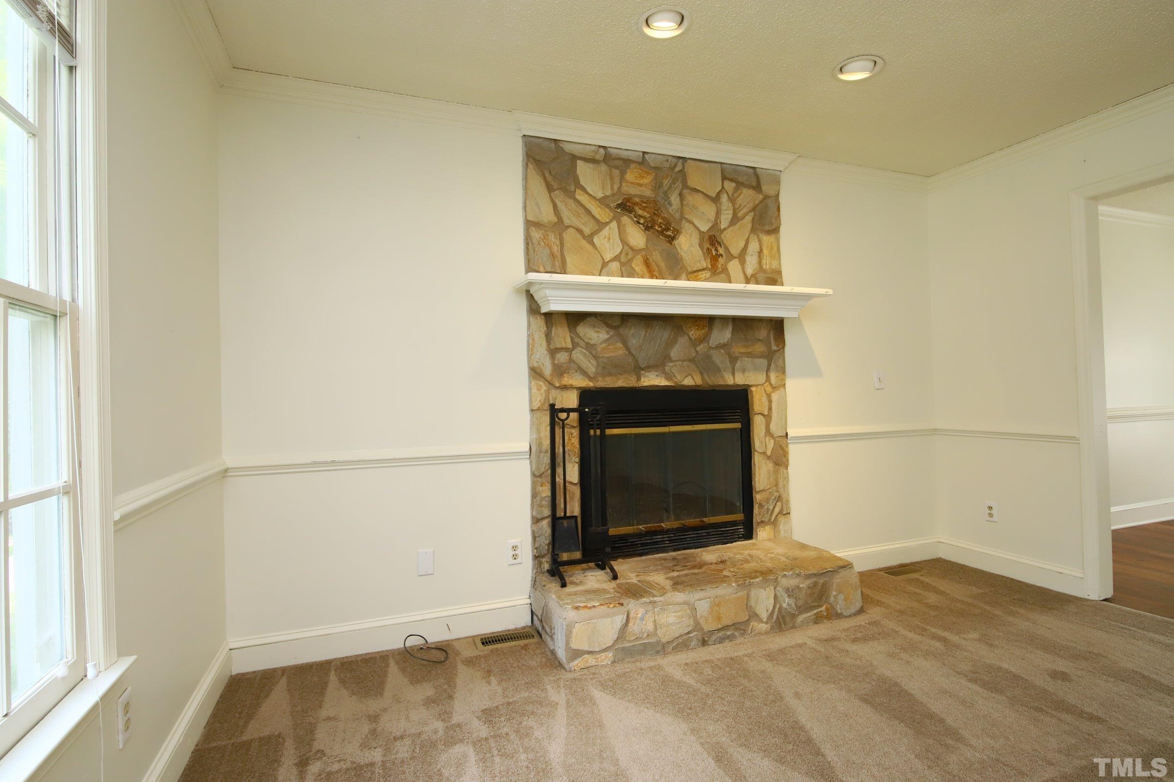 4224 Bluewing Road Raleigh, NC 27616 - Photo 6 of 29 an empty room with a fireplace and wooden floor