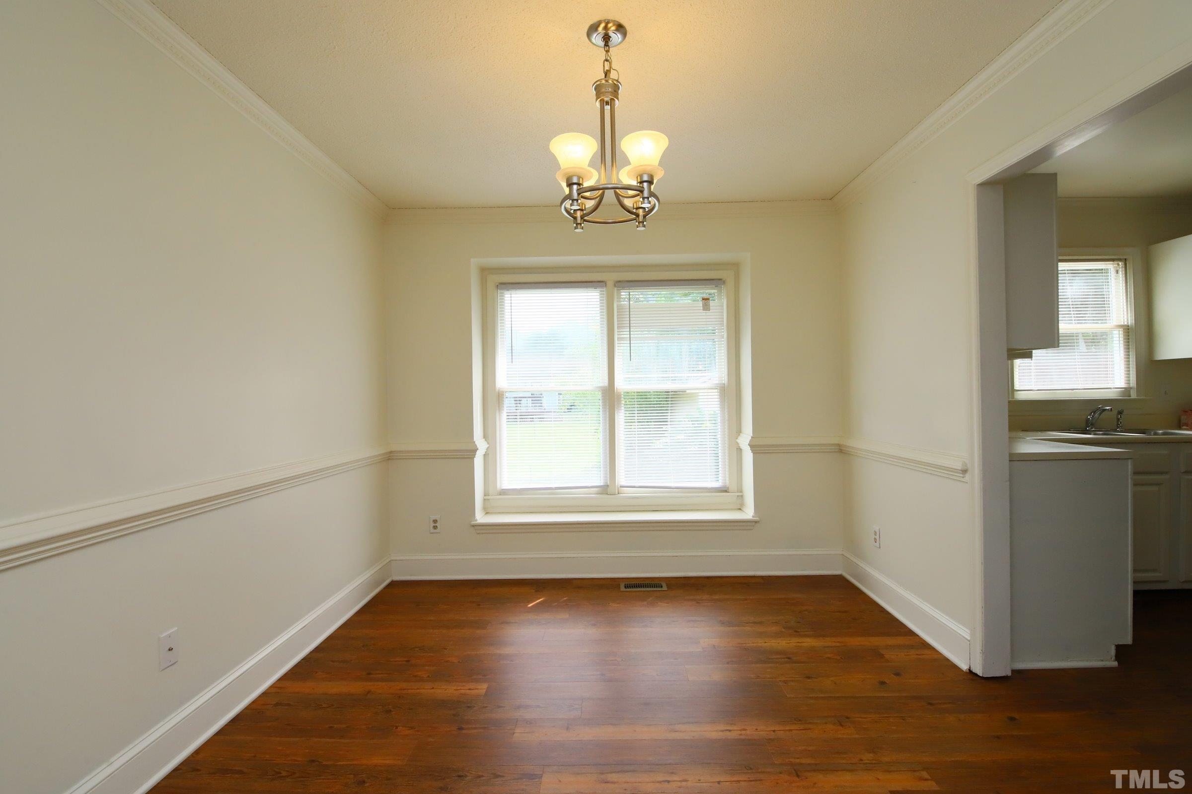 4224 Bluewing Road Raleigh, NC 27616 - Photo 8 of 29 an empty room with wooden floor cabinet and windows