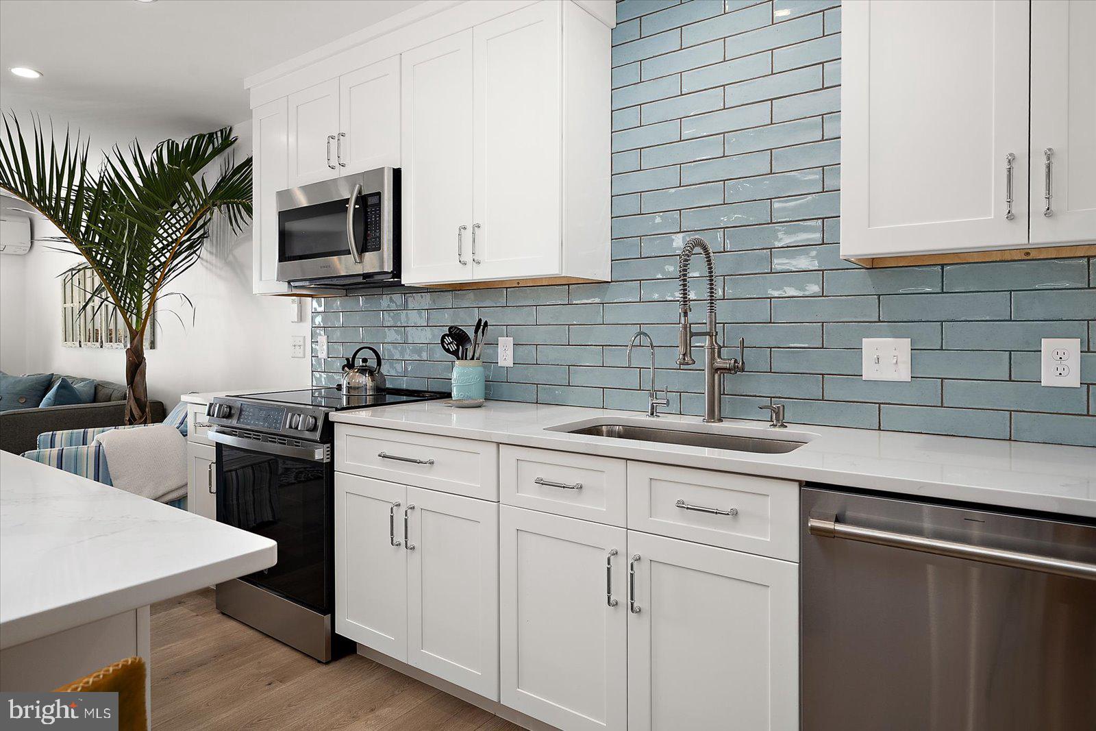 609 Dory Road, Unit 304 Ocean City, MD 21842 - Photo 19 of 55 a kitchen with white cabinets a sink stove and microwave