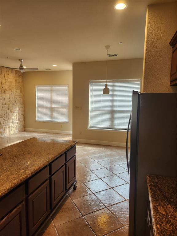 5720 Robbie Road Plano, TX 75024 - Photo 9 of 30 Built-in kitchen island with stone countertop, recessed lighting, ceiling fan, and stone accent wall