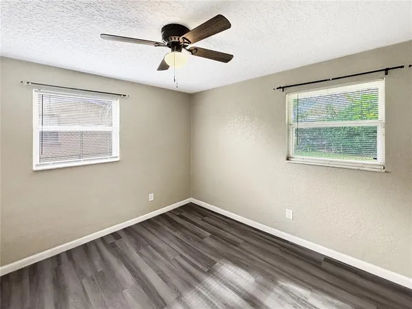 a view of an empty room with a window and a ceiling fan