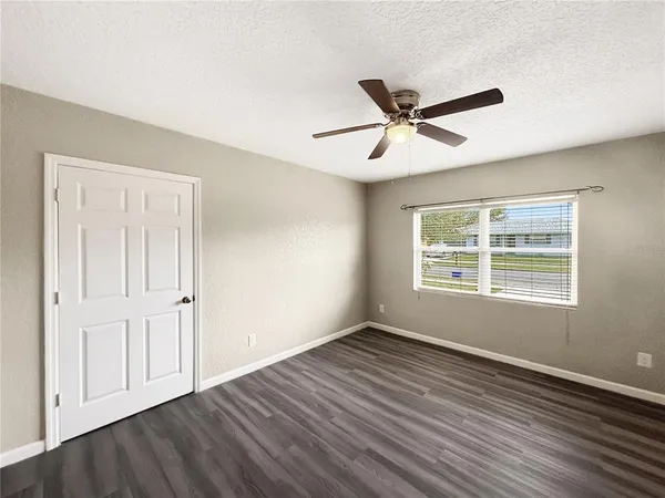 a view of empty room with wooden floor and fan