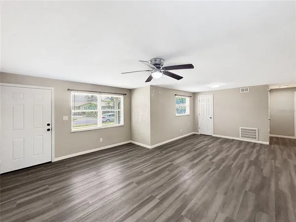 a view of an empty room with wooden floor and a window