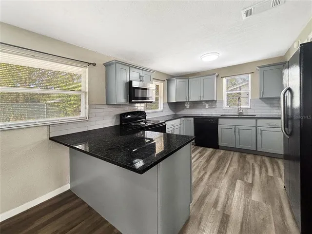 a kitchen with stainless steel appliances granite countertop a sink stove and refrigerator