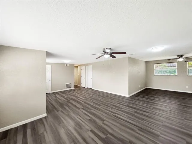 an empty room with wooden floor chandelier and windows