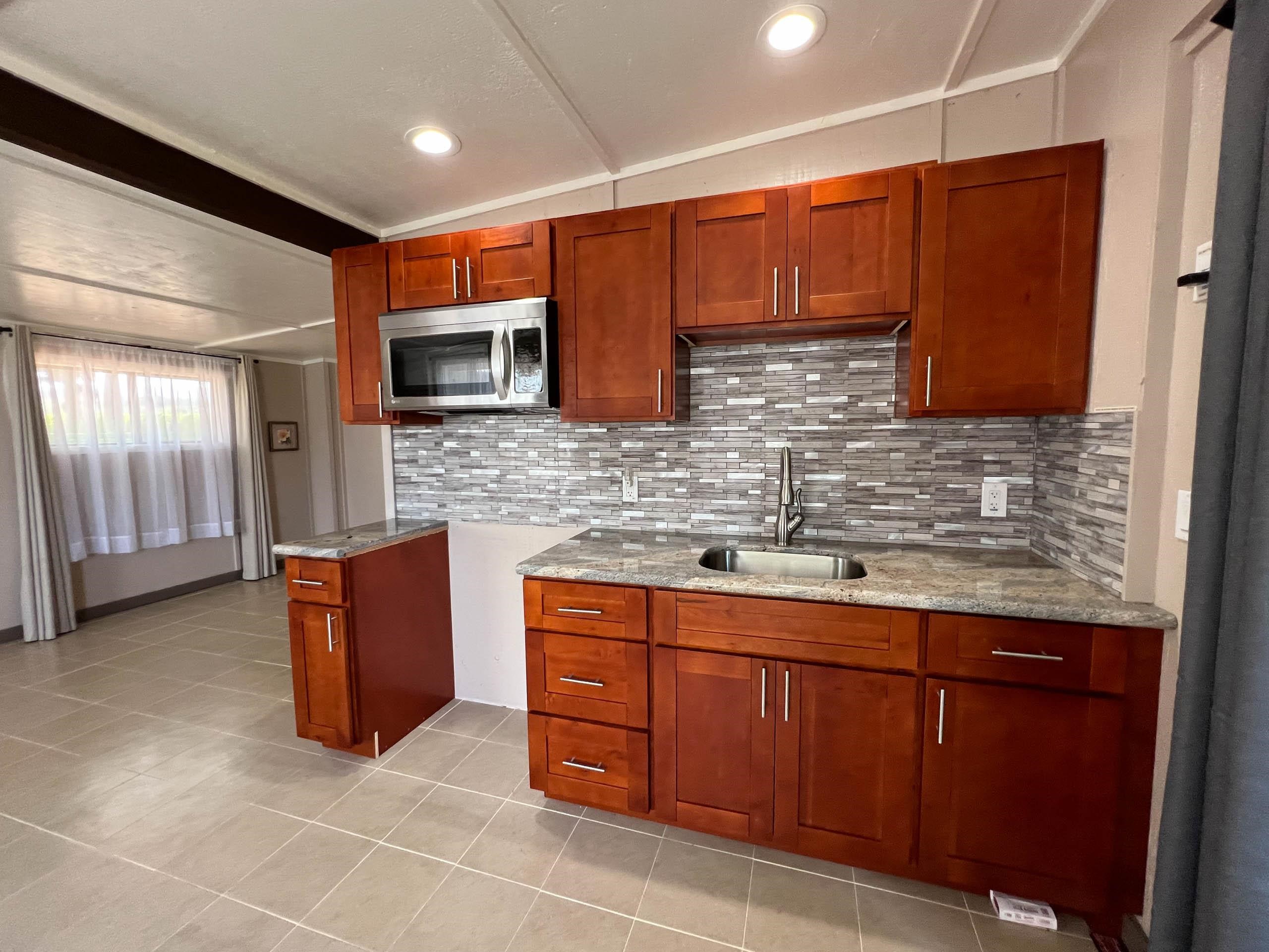 2594 Puuomalei Road Haiku, HI 96708 - Photo 21 of 30 a kitchen with stainless steel appliances granite countertop wooden cabinets a sink and dishwasher