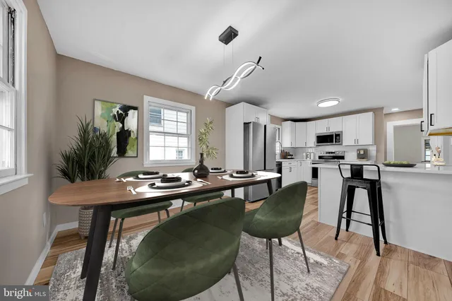 a room with stainless steel appliances kitchen island granite countertop a dining table chairs and a refrigerator