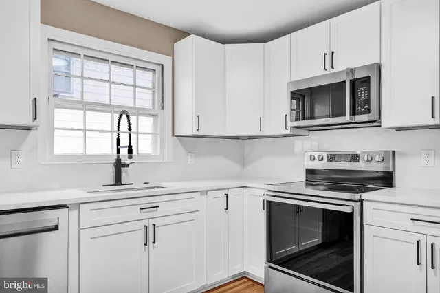 a kitchen with white cabinets appliances and a sink