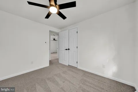 an empty room with ceiling fan and window
