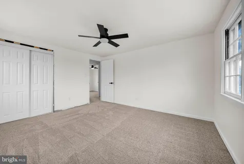 an empty room with ceiling fan and windows