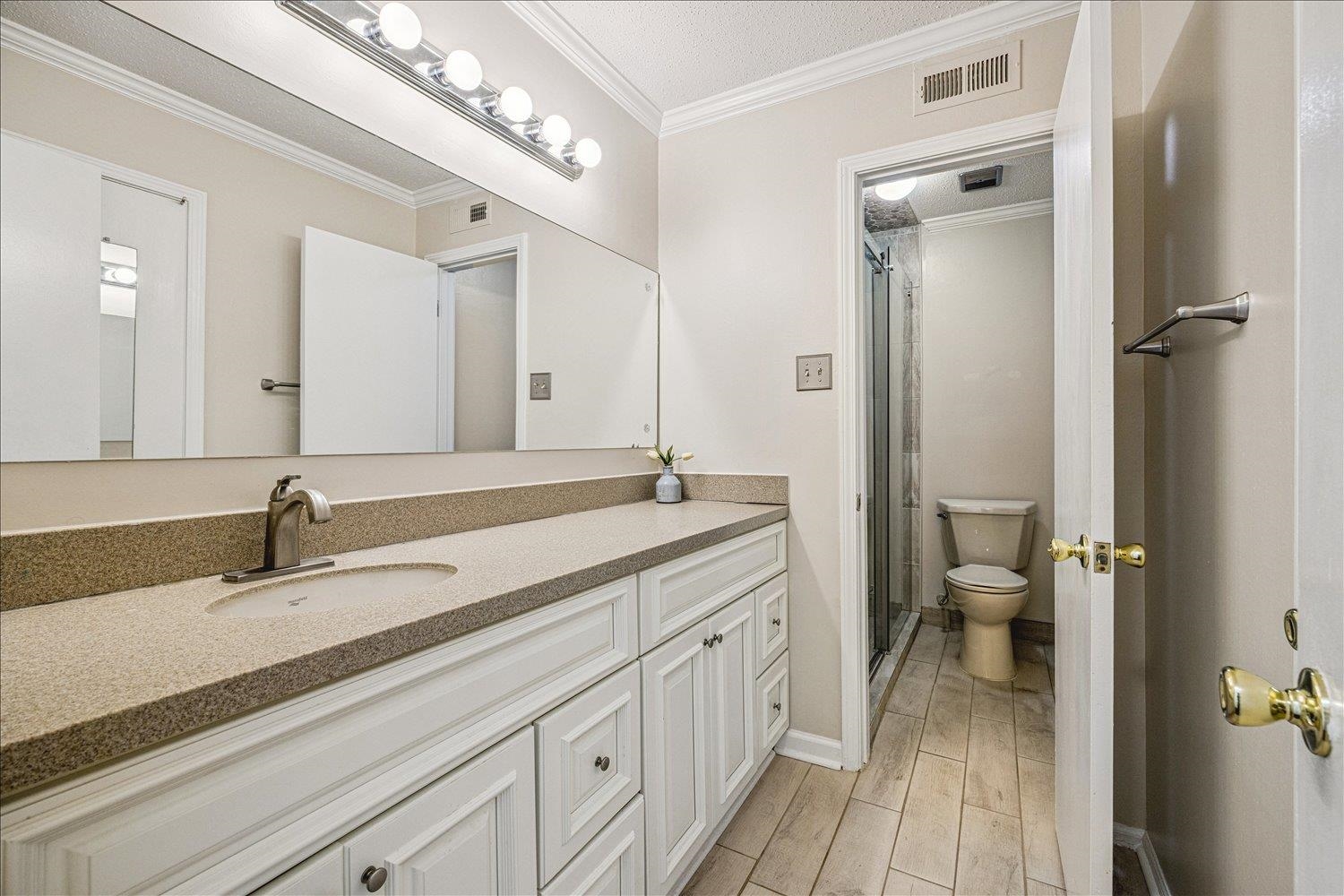 865 South Yates Road, Unit 1 Memphis, TN 38120 - Photo 12 of 25 Bathroom with crown molding, vanity, a stall shower, and wood finish floors