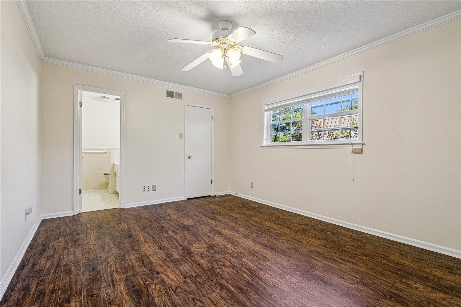 865 South Yates Road, Unit 1 Memphis, TN 38120 - Photo 21 of 25 Unfurnished bedroom with dark wood finished floors, a ceiling fan, a textured ceiling, crown molding, and ensuite bath