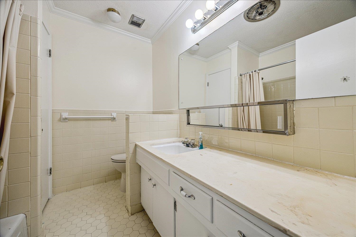 865 South Yates Road, Unit 1 Memphis, TN 38120 - Photo 22 of 25 Bathroom featuring tile walls, vanity, a textured ceiling, a shower with shower curtain, and ornamental molding