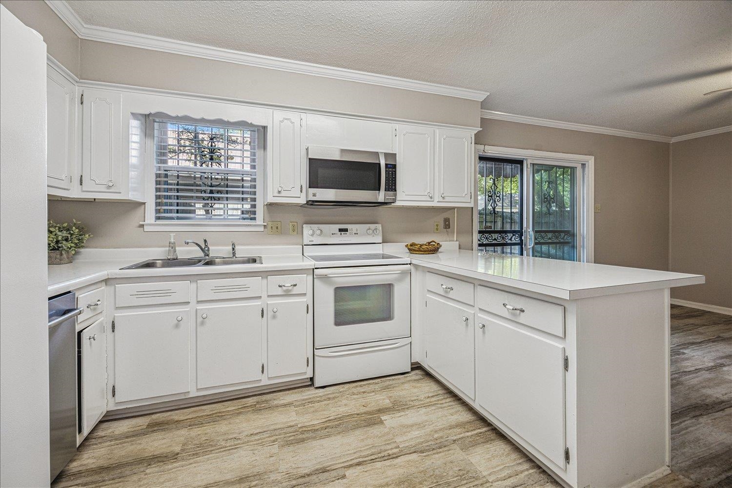 865 South Yates Road, Unit 1 Memphis, TN 38120 - Photo 5 of 25 Kitchen with stainless steel appliances, crown molding, a peninsula, light countertops, and a textured ceiling