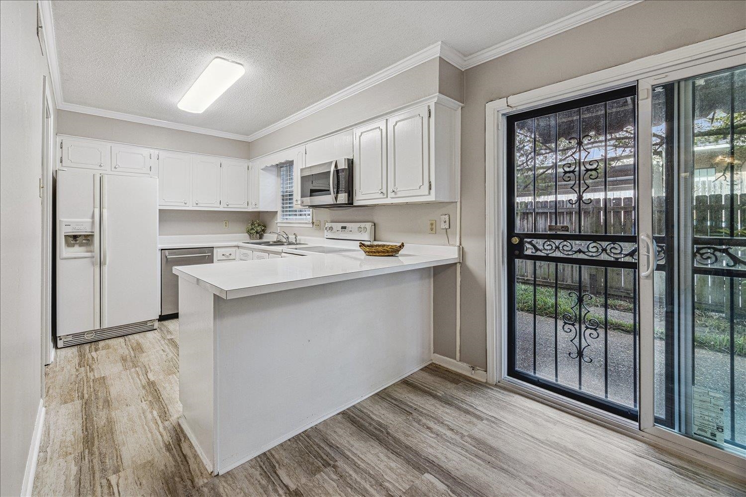 865 South Yates Road, Unit 1 Memphis, TN 38120 - Photo 6 of 25 Kitchen with light countertops, stainless steel appliances, white cabinetry, a textured ceiling, and a peninsula