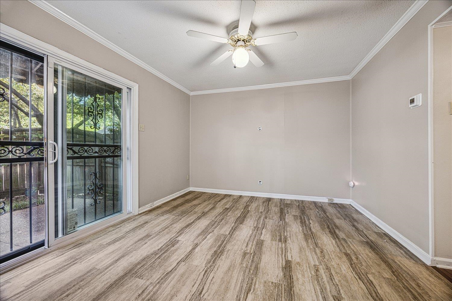 865 South Yates Road, Unit 1 Memphis, TN 38120 - Photo 8 of 25 Empty room featuring ceiling fan, light wood-style floors, a textured ceiling, and ornamental molding