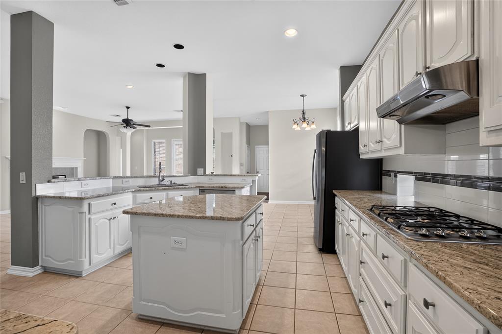 111 Ripplewood Coppell, TX 75019 - Photo 13 of 34 Kitchen featuring white cabinetry, granite countertops, an island, tile flooring, and a gas cooktop with stainless steel hood