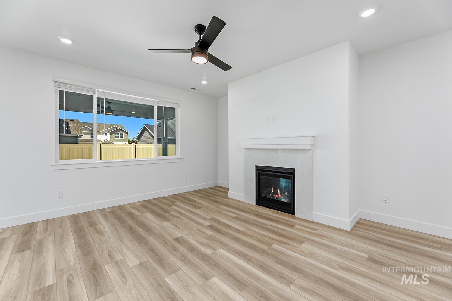 4548 West Wapoot Street Meridian, ID 83646 - Photo 6 of 17 Spacious interior featuring wood-finish flooring, a contemporary fireplace with a white mantel, and a multi-pane window