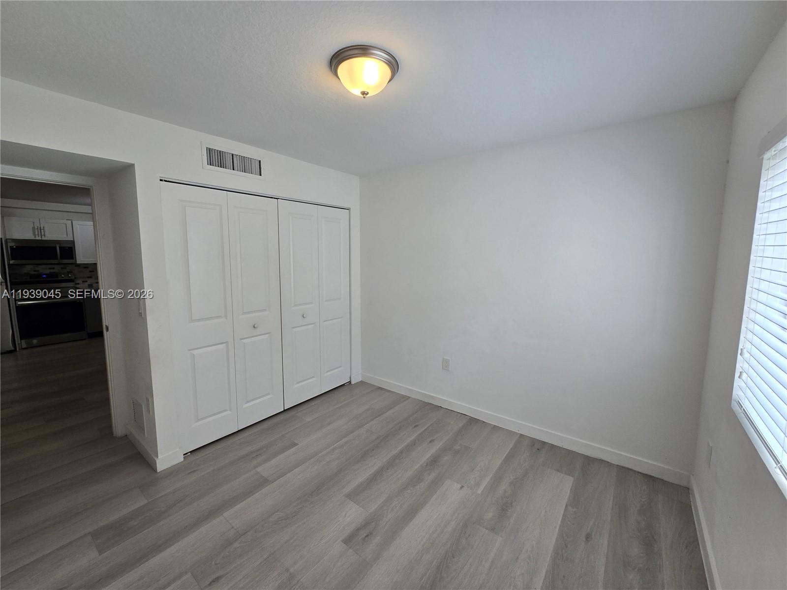 5185 West Flagler Street, Unit 204 Miami, FL 33134 - Photo 12 of 20 an empty room with wooden floor and windows