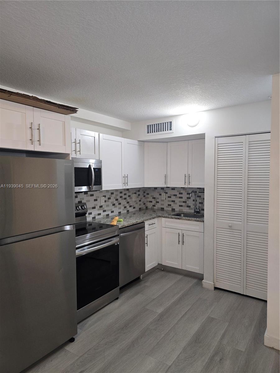 5185 West Flagler Street, Unit 204 Miami, FL 33134 - Photo 5 of 20 a kitchen with stainless steel appliances granite countertop a refrigerator and a stove top oven