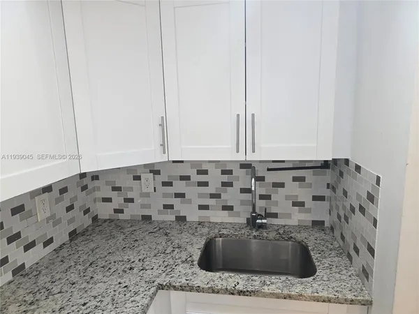 a bathroom with a granite countertop sink a mirror and bathtub