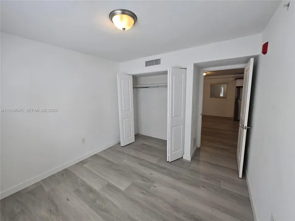 an empty room with wooden floor and mirror