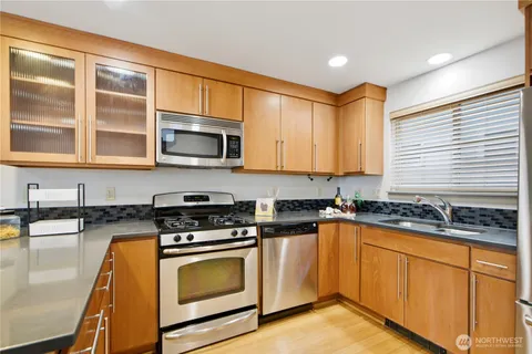 a kitchen with stainless steel appliances granite countertop wooden cabinets stove top oven and sink