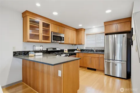 a kitchen with stainless steel appliances granite countertop a refrigerator a stove a sink dishwasher and microwave with wooden floor