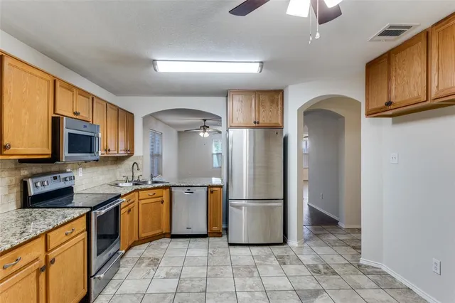 a kitchen with stainless steel appliances granite countertop a refrigerator and a stove top oven