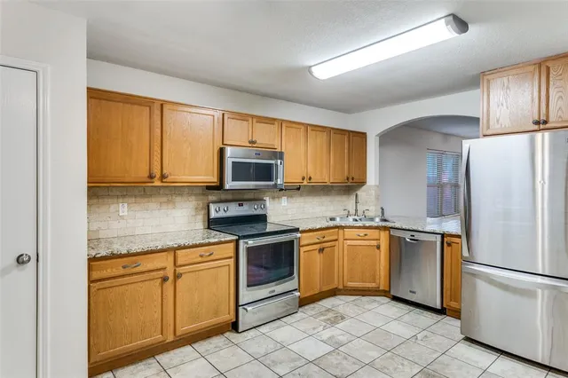 a kitchen with white cabinets stainless steel appliances and a window
