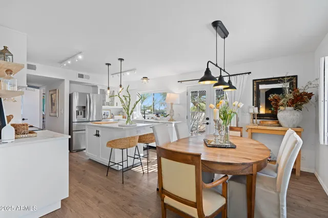 a kitchen with stainless steel appliances kitchen island granite countertop a refrigerator a stove a sink dishwasher a dining table and chairs with the cabinets