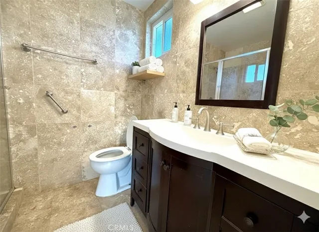 a bathroom with a granite countertop sink toilet and mirror