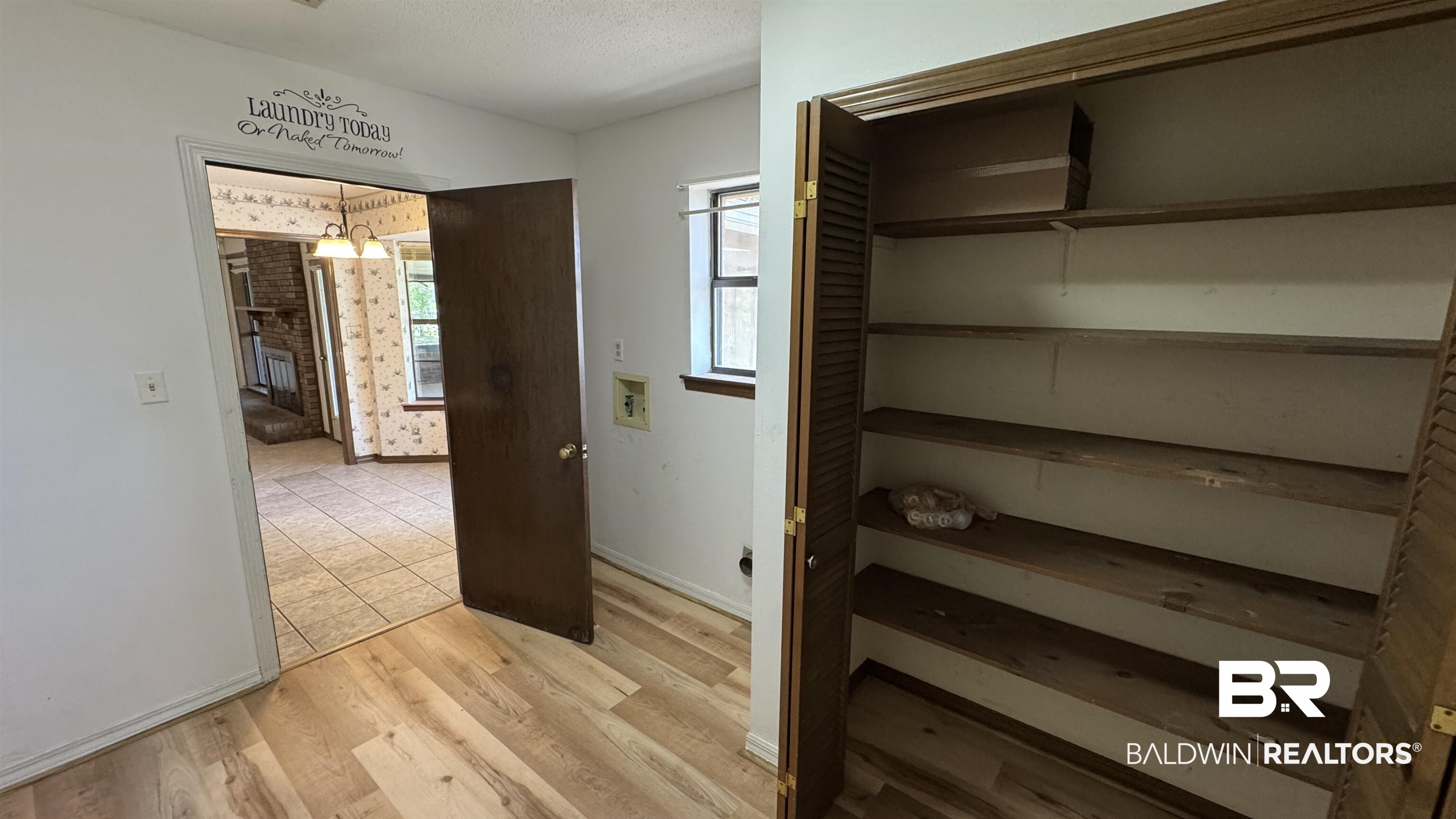 33370 Highway 98 Lillian, AL 36549 - Photo 38 of 58 Utility area with wood-finish flooring, featuring a large storage closet with louvered bi-fold doors and multiple shelving units