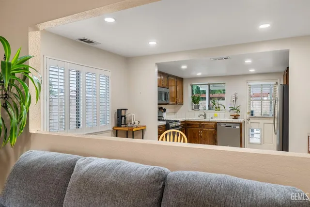 a kitchen with stainless steel appliances granite countertop a stove a sink a refrigerator dining table and chairs