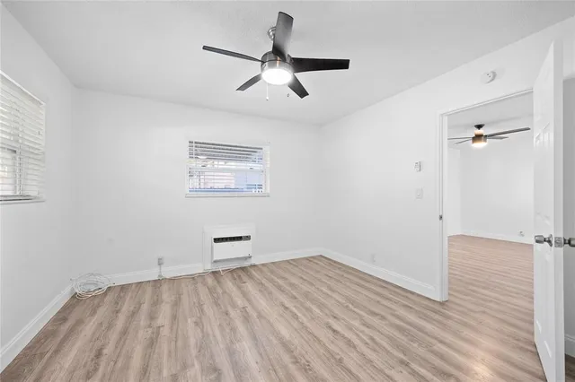 an empty room with a hardwood and ceiling fan