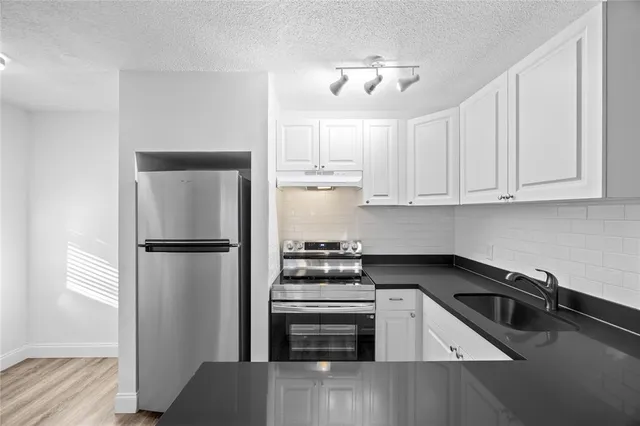 a kitchen with white cabinets and stainless steel appliances