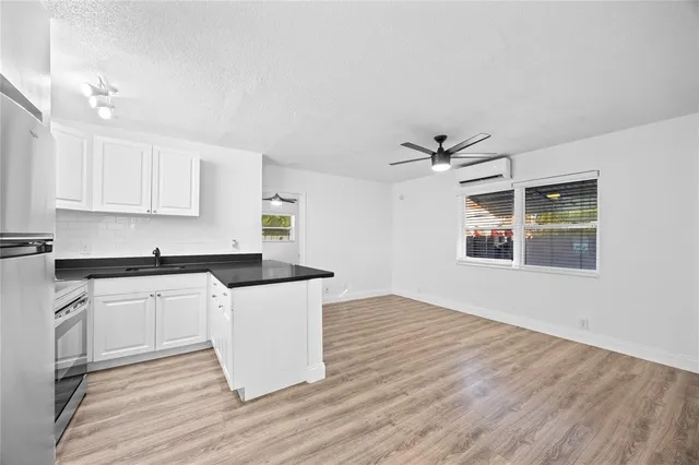 a kitchen with granite countertop a stove a sink and white cabinets with wooden floor